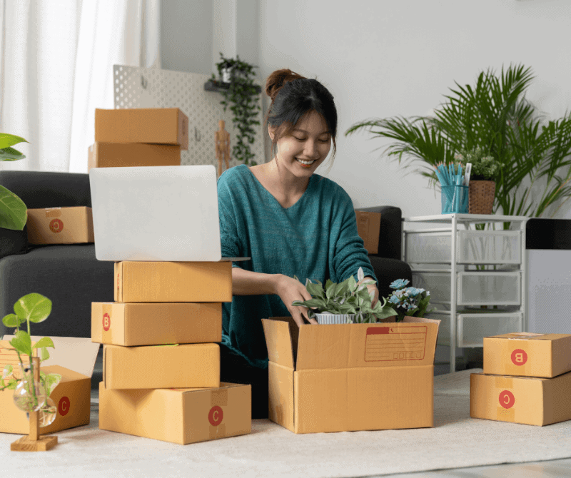 a girl packing a small plant into a box.