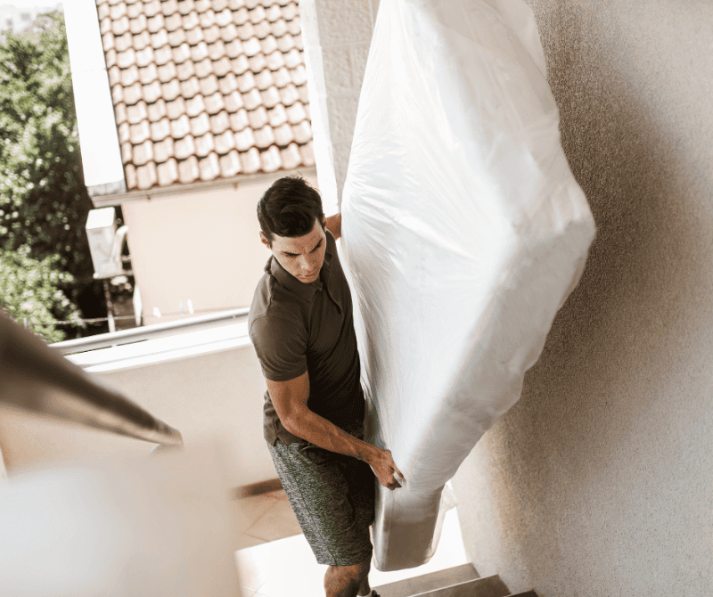 a man lifting a mattress upstairs.