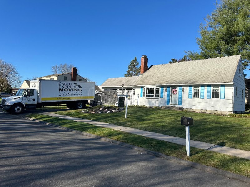 A Castle Express Moving truck parked outside a house preparing for a long distance move.