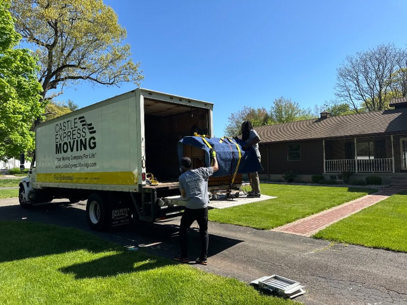 A Castle Express Moving truck with two professional moving crew efficiently and safely putting the furnitures in the truck.